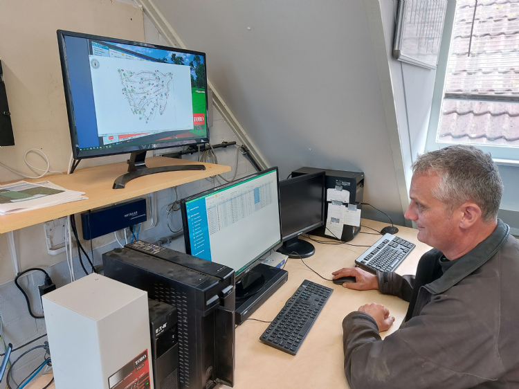 Arno de Jonge achter de pc met het Toro-besturingsprogramma. Op het scherm boven is de kaart van de golfbaan zichtbaar met alle sproeiers erop. Rechts achter dit scherm is de nu overbodige interface van Rainbird te zien. De nieuwe Toro-interface aan de an Arno de Jonge achter de pc met het Toro-besturingsprogramma. Op het scherm boven is de kaart van de golfbaan zichtbaar met alle sproeiers erop. Rechts achter dit scherm is de nu overbodige interface van Rainbird te zien. De nieuwe Toro-interface aan de an